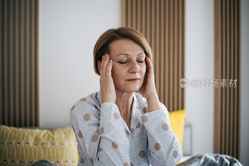 老女人因头痛而捂着太阳穴