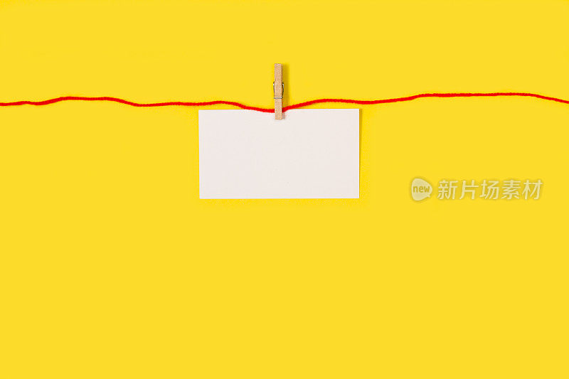 黄色背景上，红线挂着一张空白的白纸