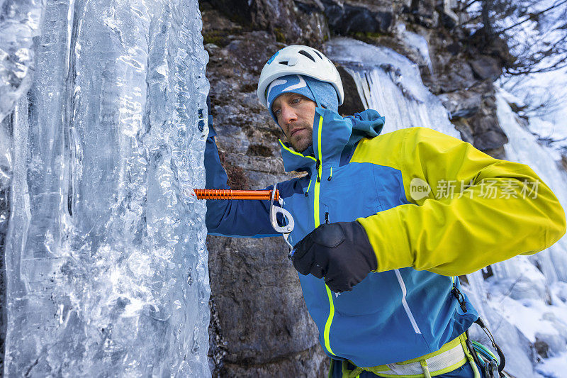 冰攀者在冰冻的瀑布中转动冰螺钉