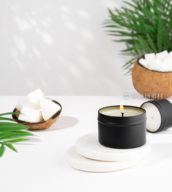 椰子蜡蜡烛在一个黑色的罐子，绿色的叶子，植物在一个白色的背景。天然环保椰子蜡烛。时尚的概念。极简主义者。等角投影。副本的空间。