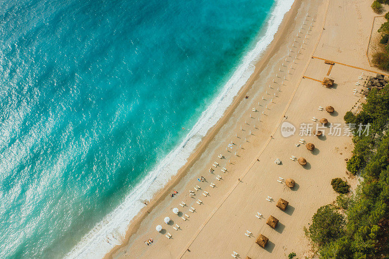 在土耳其的Oludeniz，打着遮阳伞的梦幻般的绿松石海滩鸟瞰图