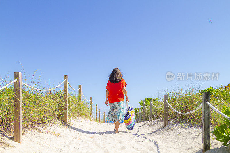 一名年轻的拉丁女子在世界著名的迈阿密海滩享受一日游，美国佛罗里达州南海滩，美国，阳光照亮在一个蓝色阳光灿烂的夏日中午。