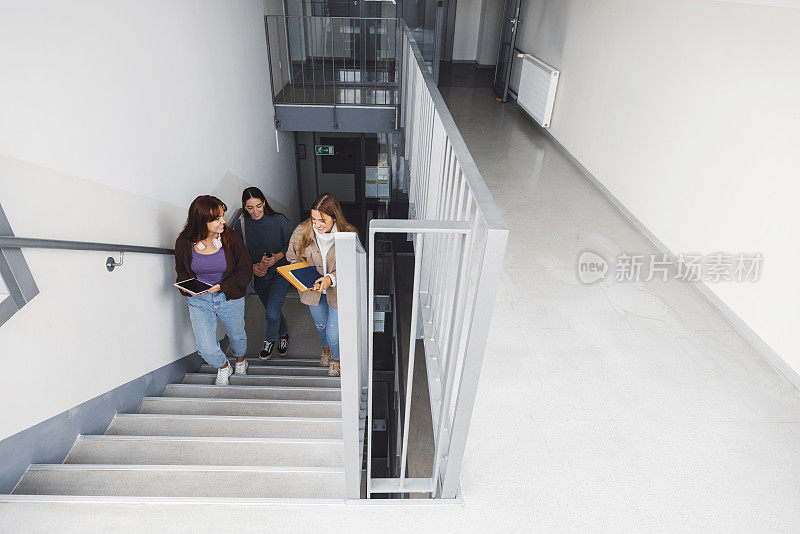 从楼梯顶端看，三个女学生正走上楼梯