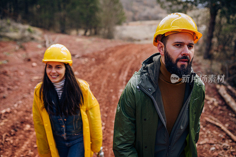 两个年轻的工程师走在森林的道路上