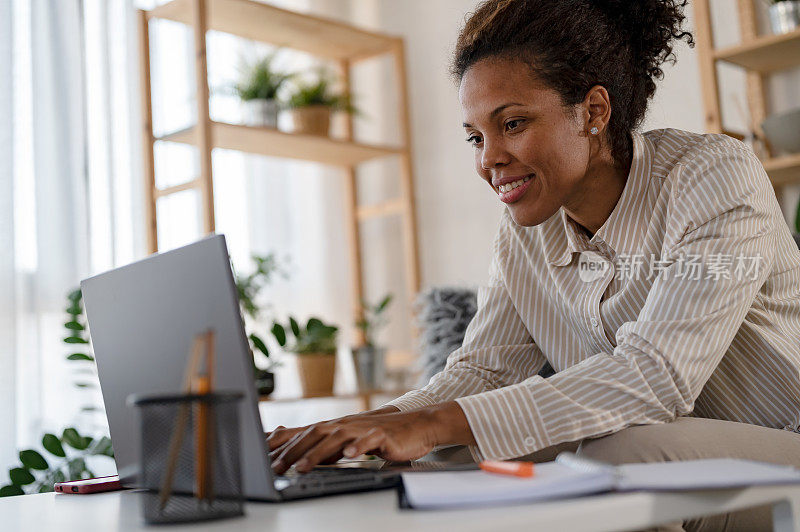 年轻的非洲民族自由职业者妇女在笔记本电脑在家庭办公室工作。远程工作
