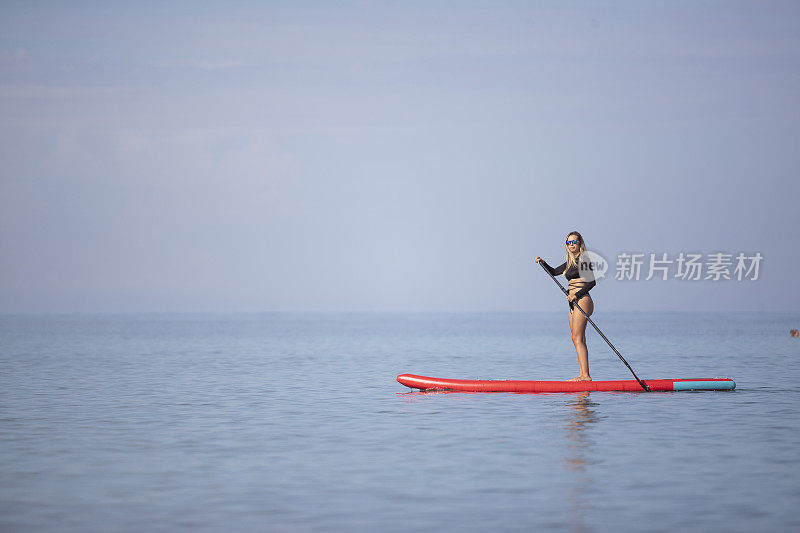 一名女性冲浪者在SUP板上划桨时享受和平与安静