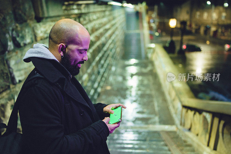 年轻的拉丁裔男性成年人在户外玩电子游戏用手机