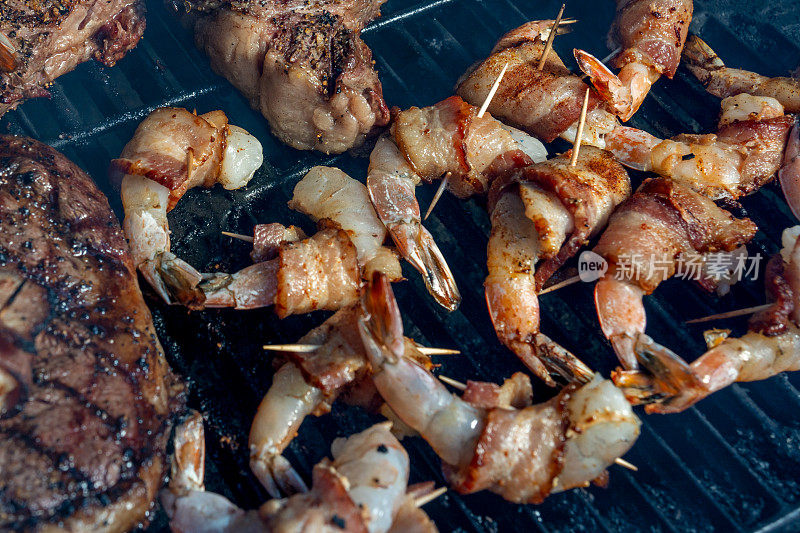 培根包裹的巨型虾和肋眼牛排在老式木炭烧烤，完全煮熟，随时可以吃