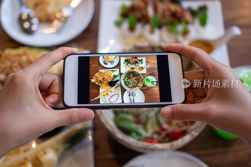 午餐或晚餐时用智能手机拍张照片。女人用手机拍照。在社交媒体上发布或分享流行的食物。