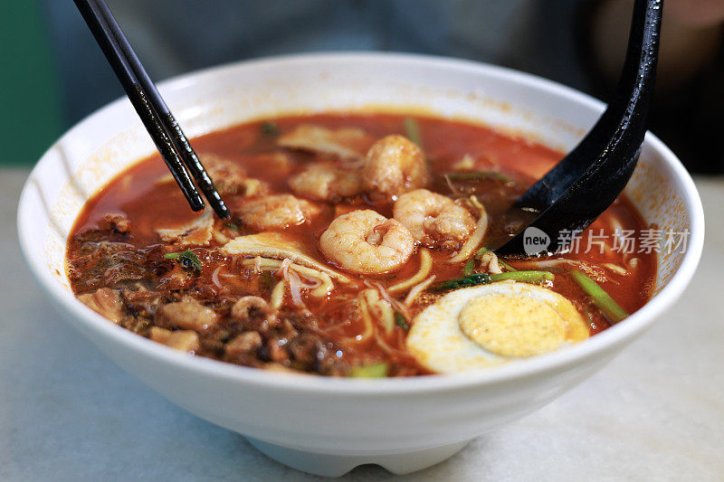 一名亚洲妇女品尝槟城闽南味，这是马来西亚一种很受欢迎的街头小吃。