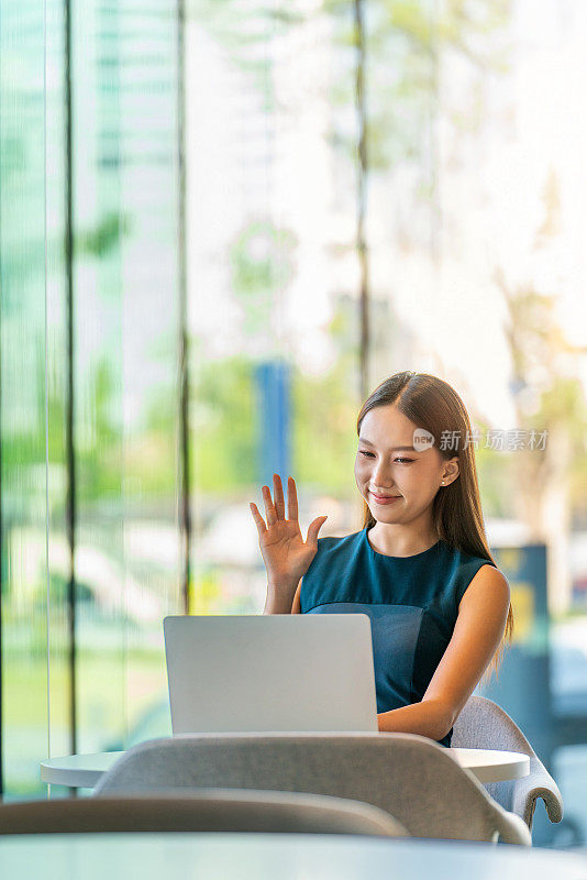 亚洲女商人一边在办公室外用笔记本电脑工作，一边开在线团队会议