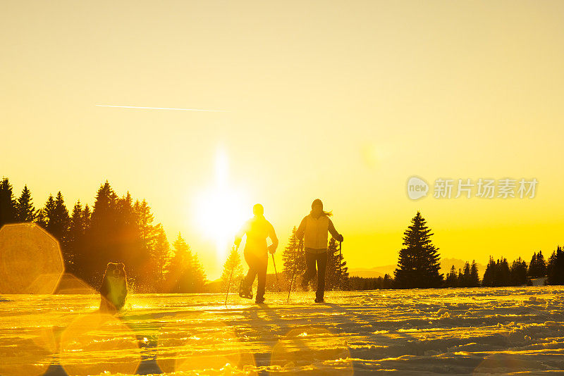 滑雪者带着宠物狗在雪坡上奔跑的剪影