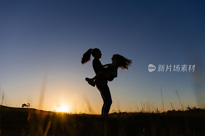 夕阳下田野里母亲抱着女儿的剪影