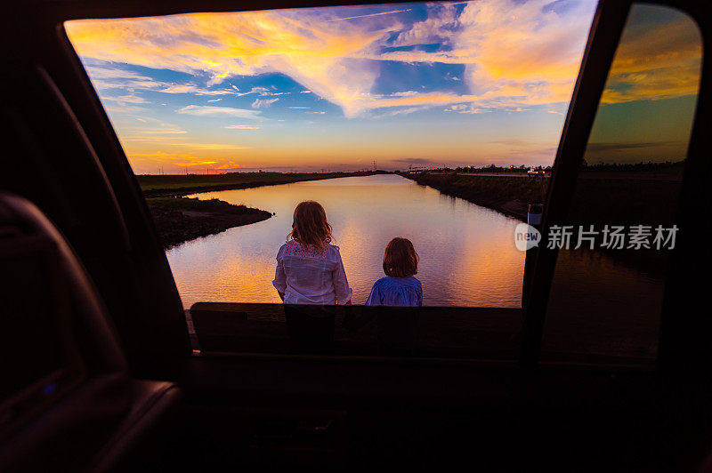 女孩们在公路旅行，在假期的加油站看着美丽的日落