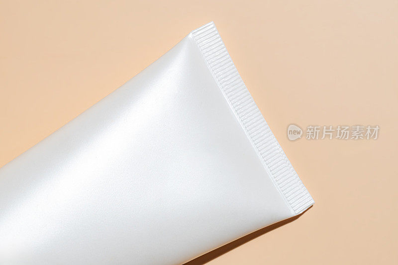 白色挤压瓶塑料管的模型，用于药品或化妆品的品牌-面霜，凝胶，护肤品，牙膏。化妆品瓶容器上的米色背景。极简主义