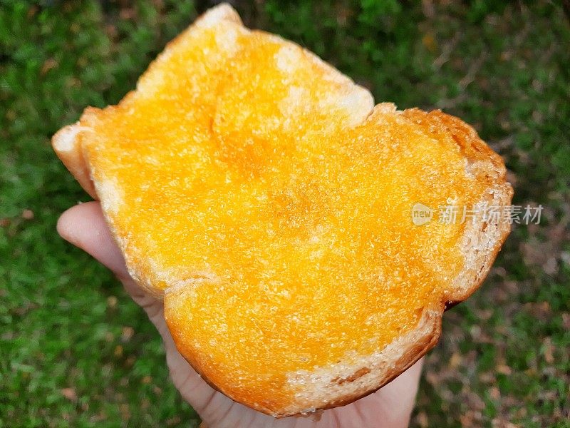 手握甜吐司黄油面包-曼谷街头食品。