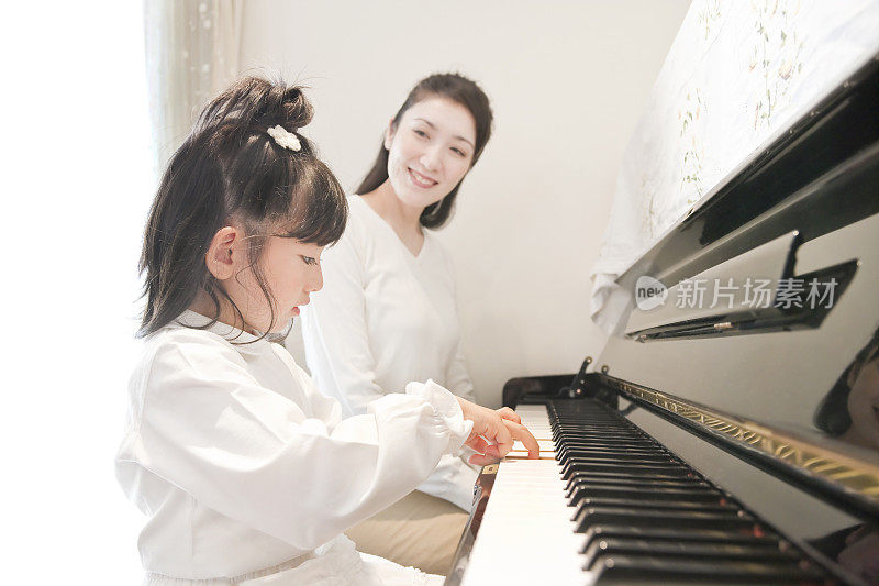 母亲看着女儿弹钢琴