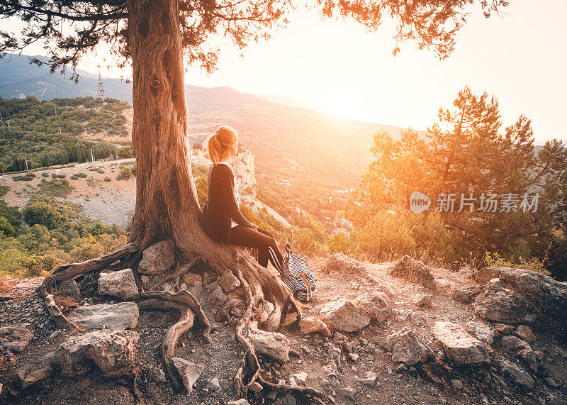 日落时坐在山上的年轻女子。夏天的风景