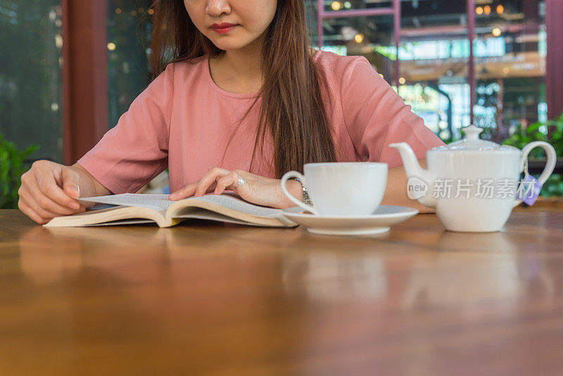 年轻女子在花园里看书喝茶