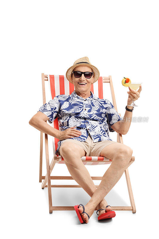 年长的游客拿着鸡尾酒坐在阳光躺椅上