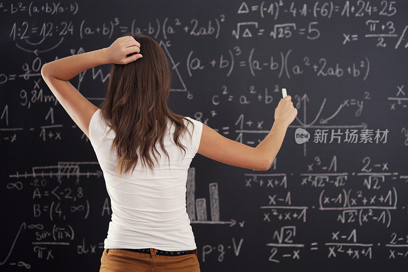 一位年轻女子正在看黑板上的数学题