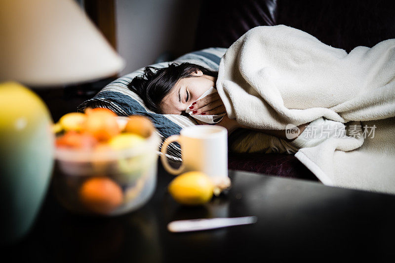 流感。女人感冒了病毒生病的女人躺在床上盖着羊毛毯子