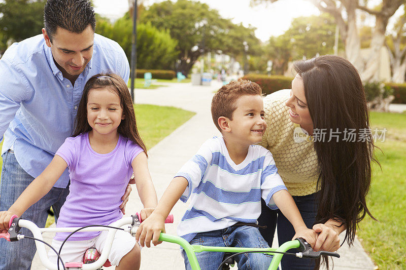 父母教孩子在公园里骑自行车