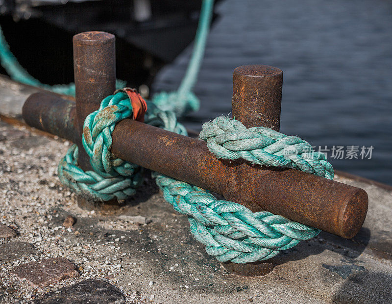 绿色尼龙系泊绳系在生锈的船坞钩上