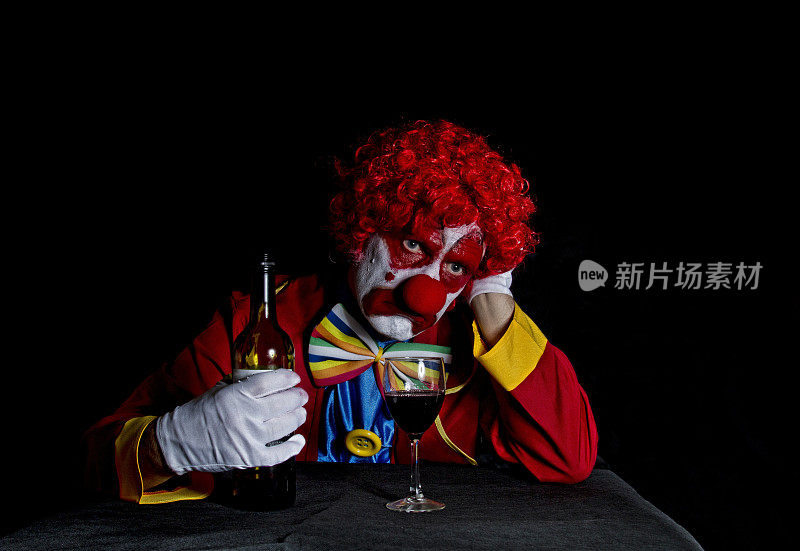 小丑悲伤的脸靠在桌子上喝酒