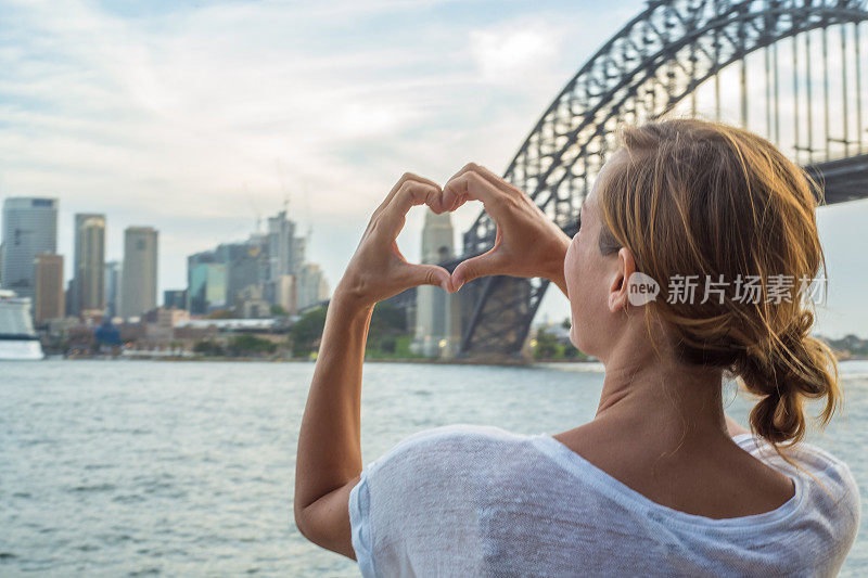 一名女子用心形手指框勾勒出悉尼的天际线