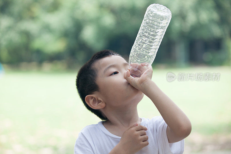 亚洲男孩用塑料瓶喝酒