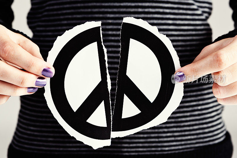 寻找和解，女性的双手紧握撕裂的和平标志，