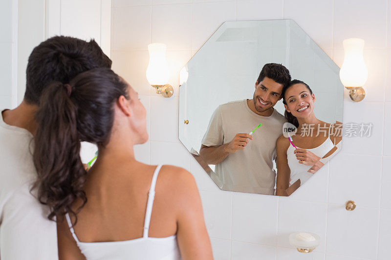 一对微笑的夫妇在刷牙时照镜子