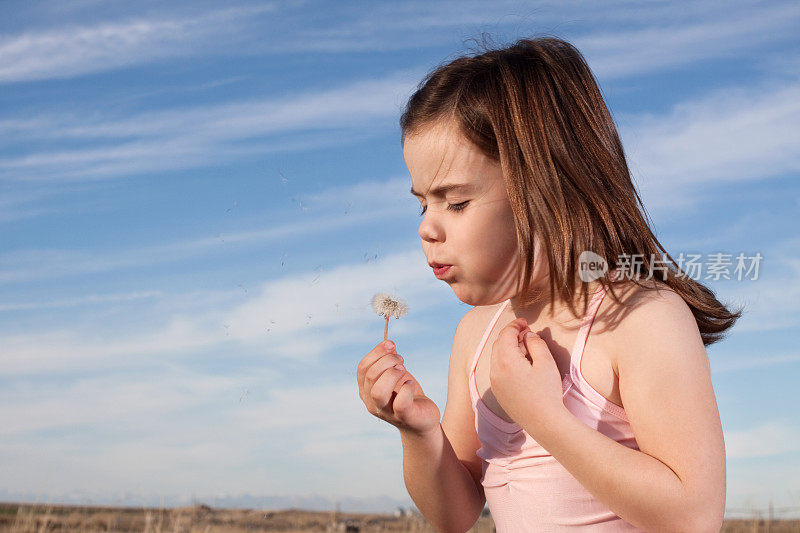 小女孩在蒲公英上许愿