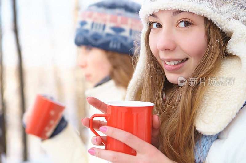 在冬天的户外。女孩喝茶。