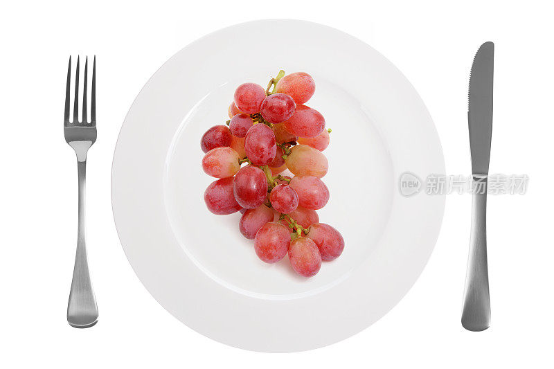 盘子上的葡萄和白色背景上的刀叉