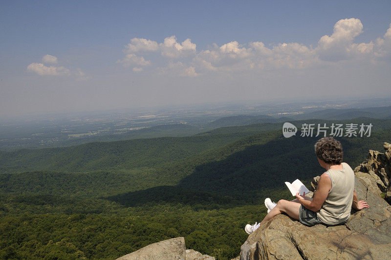 徒步旅行者在山顶读书