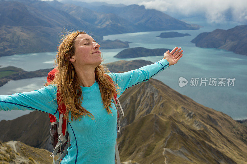 年轻女子的肖像在山顶上张开双臂