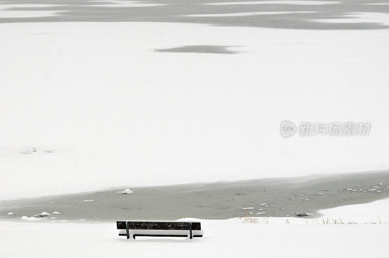 结冰的斯皮辛湖岸边，铺满雪的木制长凳