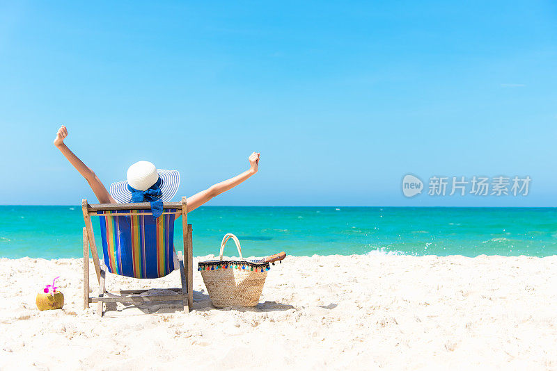 暑假。美丽的年轻亚洲女人放松和快乐的沙滩椅与鸡尾酒椰子汁