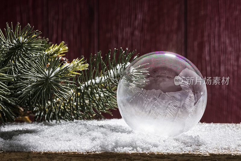 红色谷仓旁的雪地上有结冰的肥皂泡