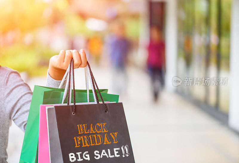 女人拿着购物袋在购物中心与黑色星期五的单词概念。