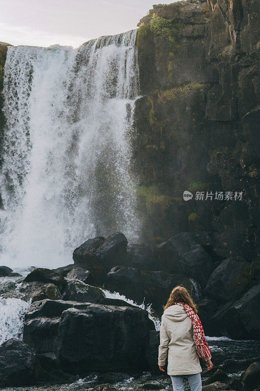 一个女人在山上的瀑布附近散步