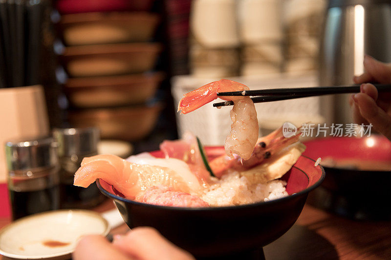 日本妇女吃海鲜寿司在碗