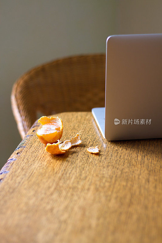 真正的房子:打开的笔记本电脑，木桌，吃了一半的橘子