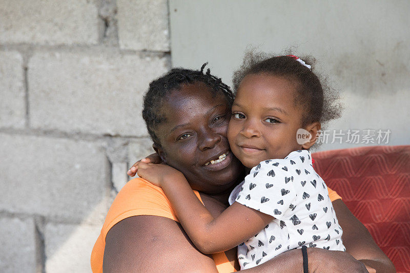 一个来自偏远村庄的牙买加母亲拥抱她的小女儿的肖像
