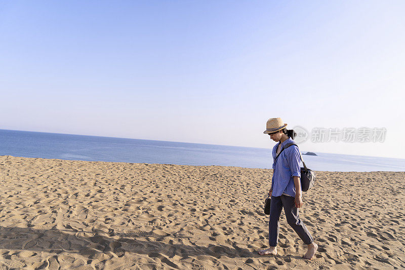 女游客走在沙丘上望着大海
