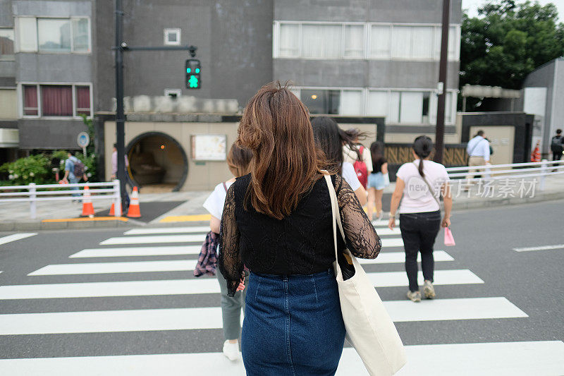 一名女子走在表参道大街上，这是日本最著名的街道之一