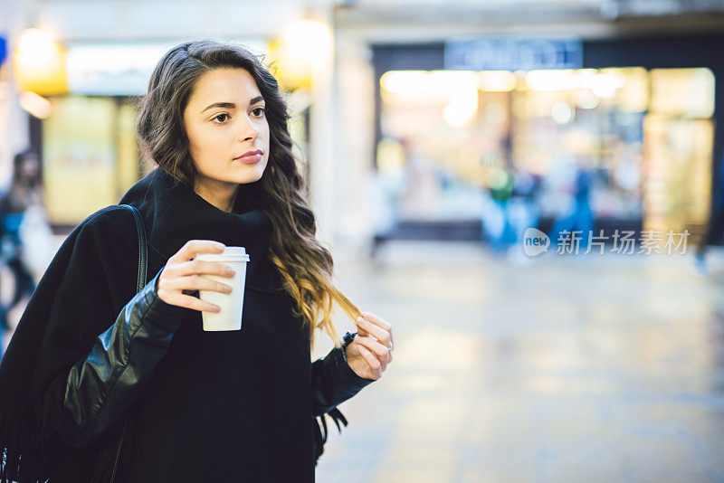 拿着一杯热咖啡在城里走来走去的女人。