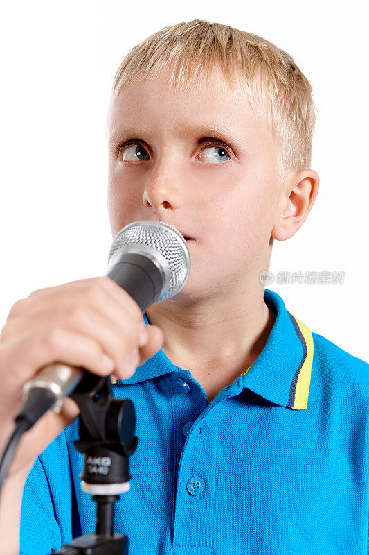 金发小男孩对着麦克风说话或唱歌